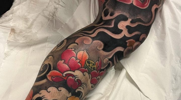 Japanese-style sleeve tattoo with a red mask, flowers and black waves