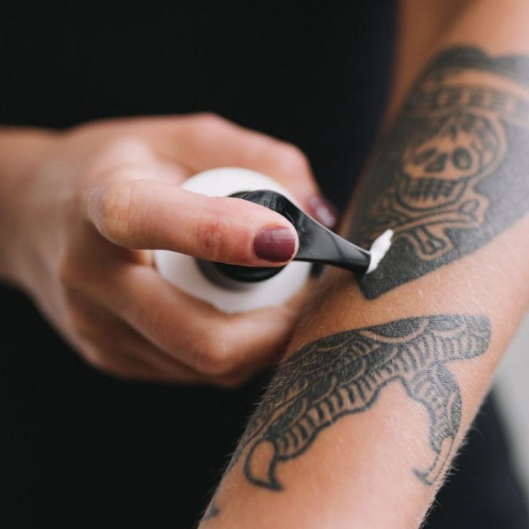 Applying cream to a tattooed forearm