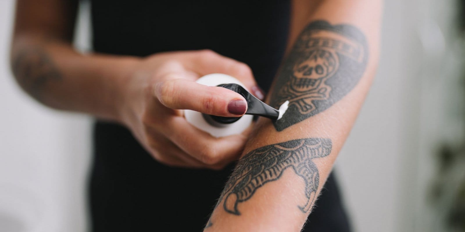 Applying cream to a tattooed forearm